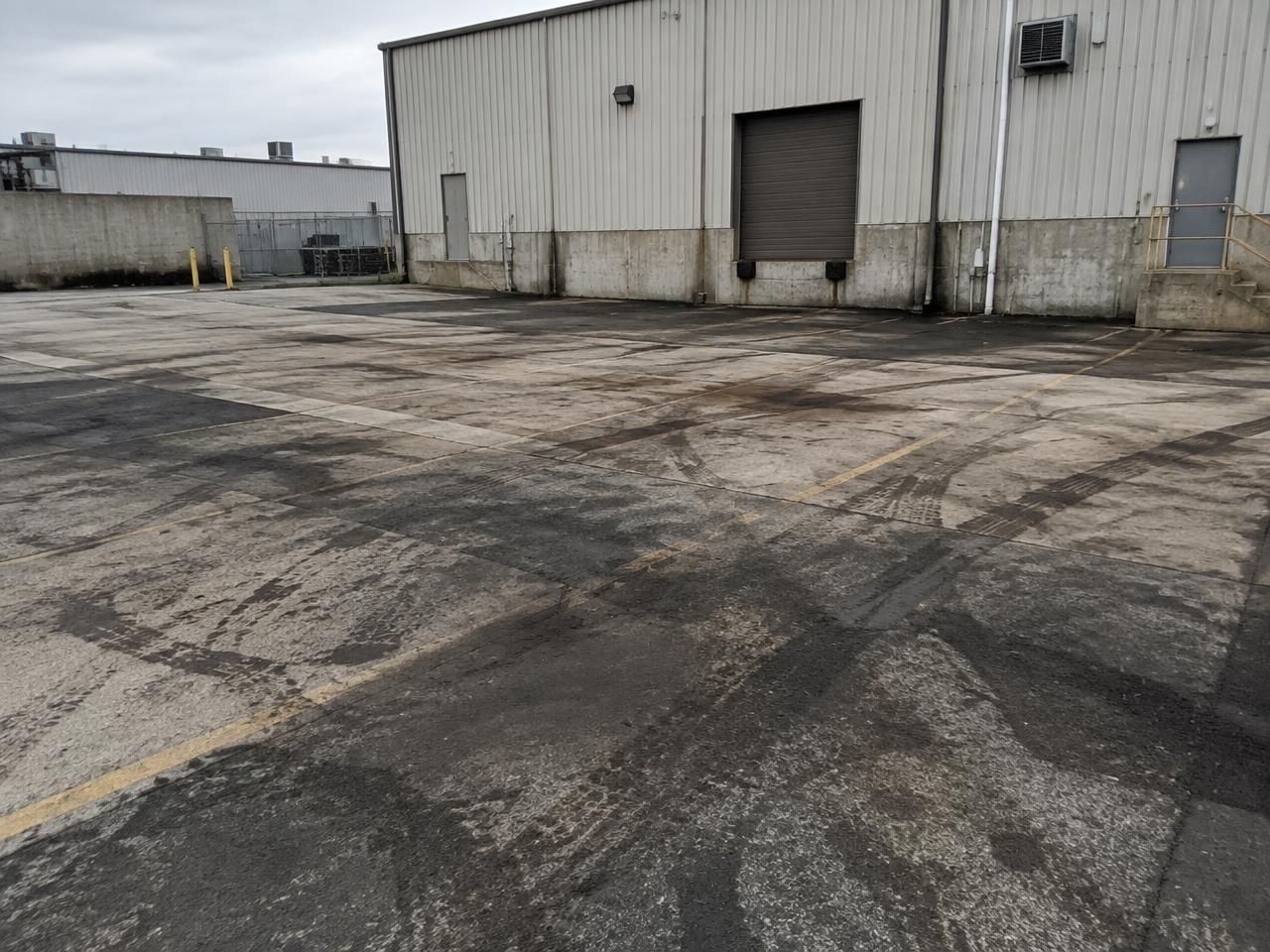Industrial parking area with oil staining, tire marks and built-up grime over the pavement